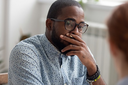 Unpleasantly surprised african-american businessman listening female caucasian coworker whirlwind